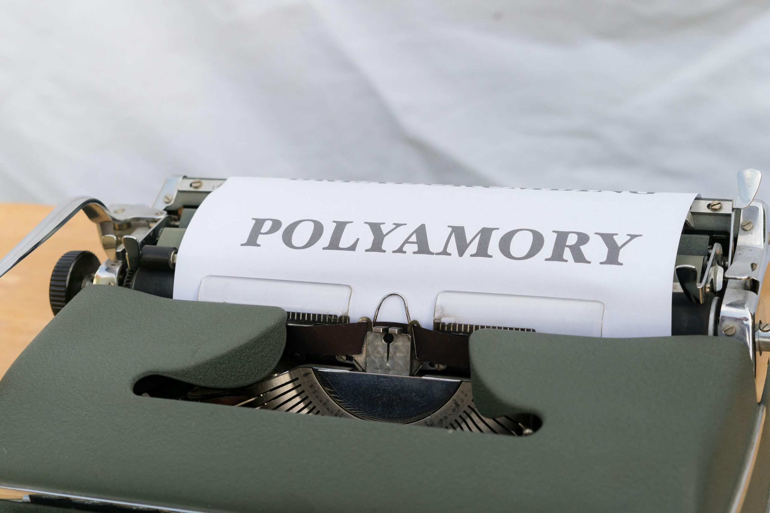 Typewriter with 'POLYAMORY' text on paper, vintage and conceptual image.