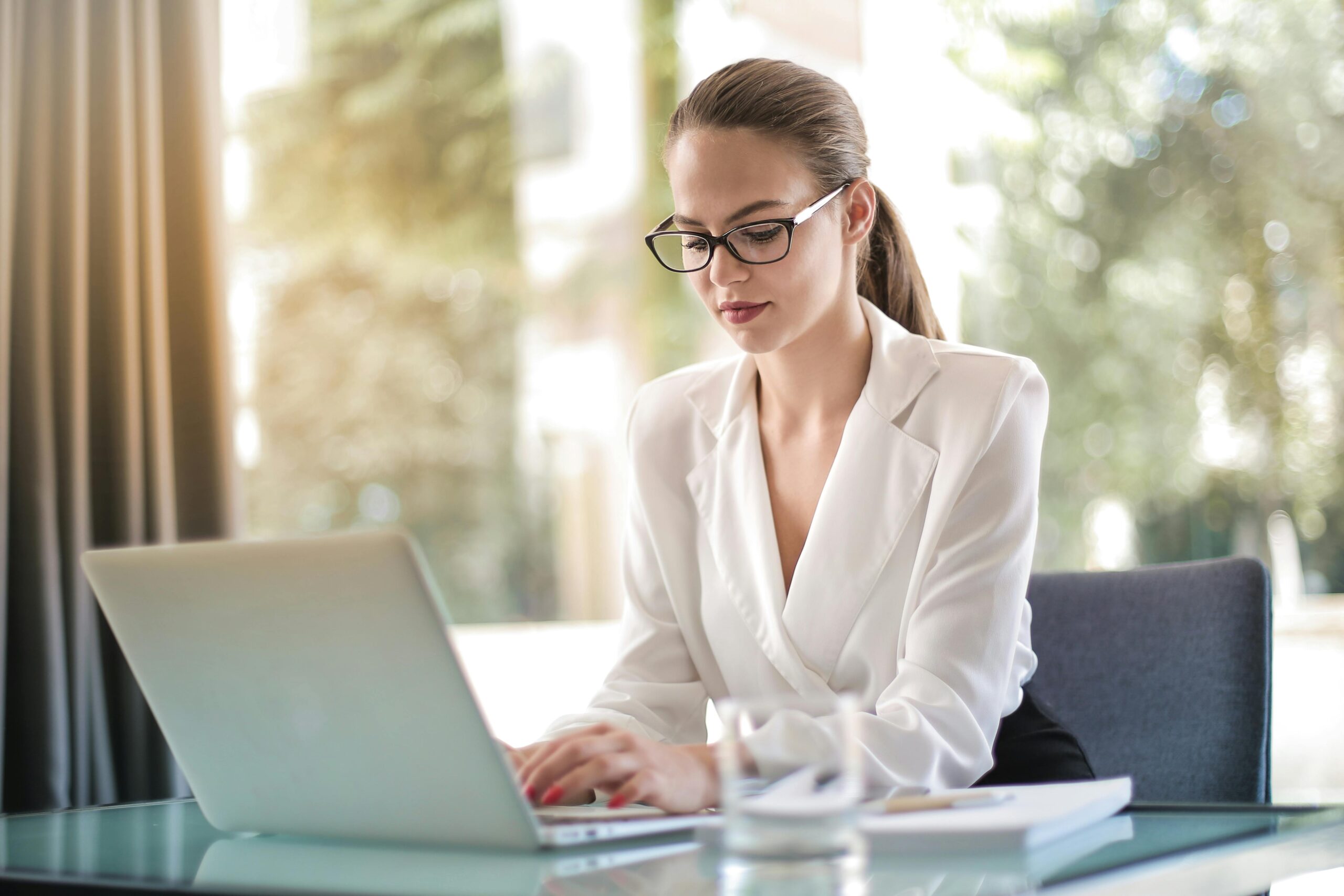 Confident businesswoman using a laptop at her desk, focused on her work.