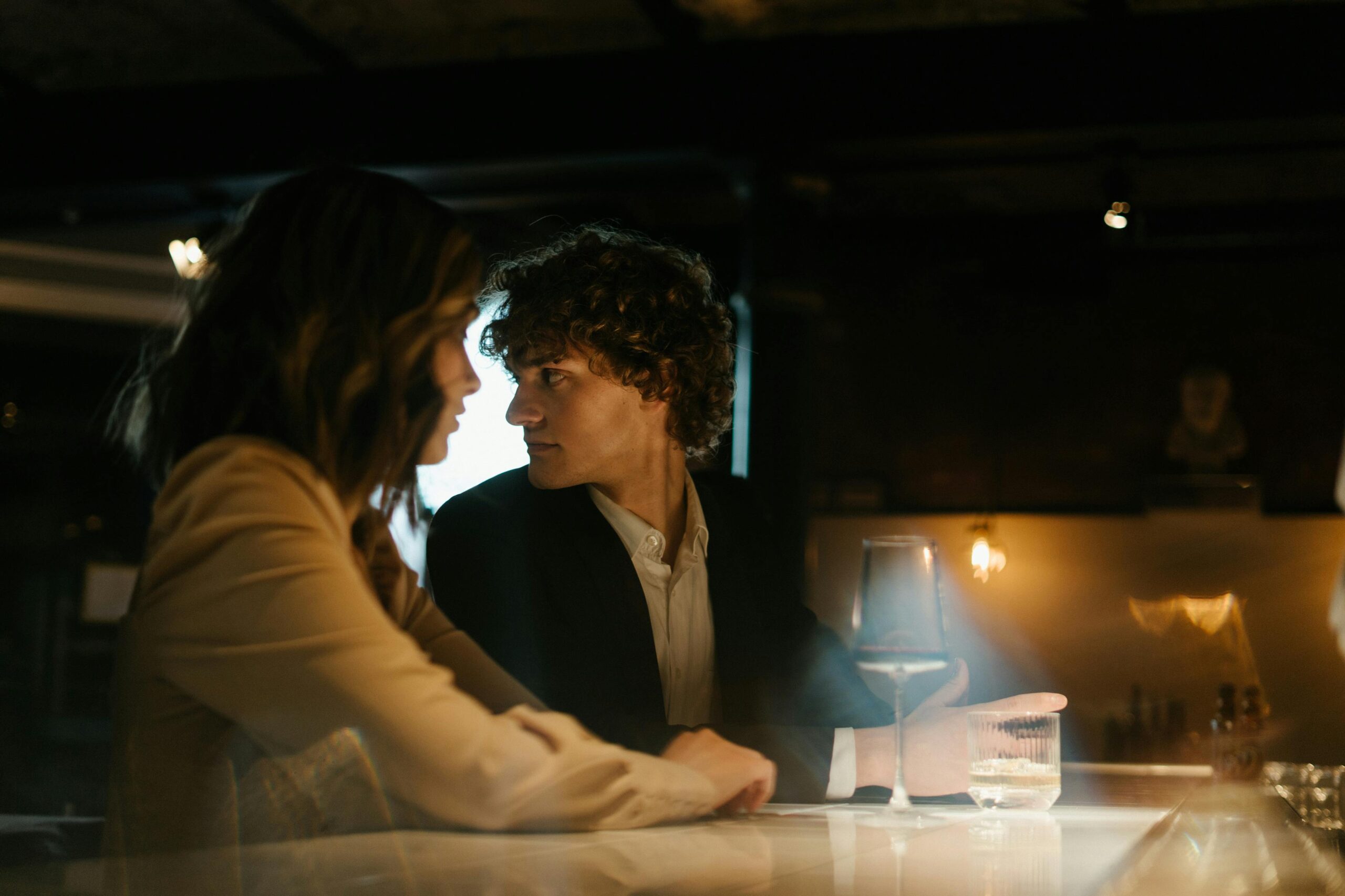 Young couple enjoying a romantic evening at an elegant bar. Warm lighting sets a cozy atmosphere.